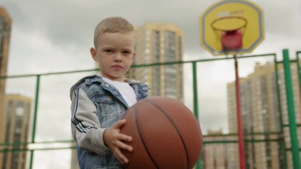 Junior Schoolboy Holds Basketball Hands Sports Ground Basketball Hoop Dwelling — Vídeo de Stock