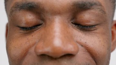 Calm look of African-American young man with freckles and thick wide dark eyebrows. Face of guy with big nose and large brown eyes having clean shaved skin extreme closeup