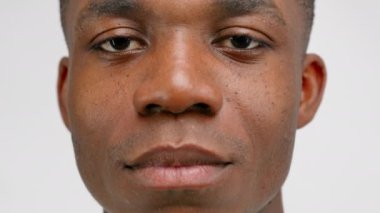 Adult African-American guy changes facial expression from sad to cheerful. Clean shaved man with chubby lips smiles with teeth on white studio background closeup