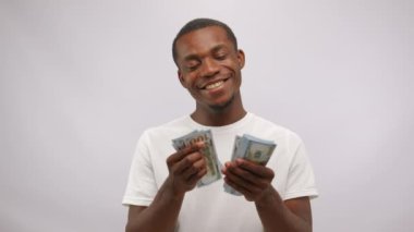 African American man counts earned monthly salary from casting. Young actor shows sketch about favourite job calculating banknotes at white studio wall