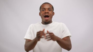 Young black man touches face and head looking with shocked expression. African American cast member hears amazing news on open audition in white studio