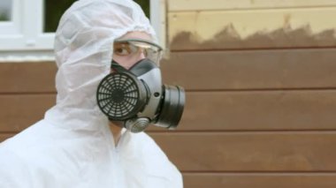 Portrait of man painter in protective suit glasses respirator looking at camera. He is turning to camera putting off respirator and breathing free. Copyspace for text in frame. Renovation concept.