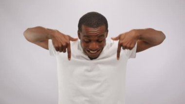 African American man points fingers downward to advertise special product. Young black cast member demonstrates toothy smile advertising in white studio