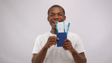 African American man holds tickets to visit favourite country. Young cast member looks with excited and delighted expression and ready to travel across different places