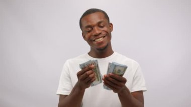 African American man counts earned monthly salary from casting. Young actor shows sketch about favourite job calculating banknotes at white studio wall