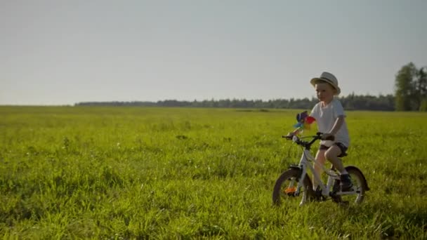 Relaxed Boy Hat Shorts White Shirt Riding Bike Windmill Green — Stockvideo