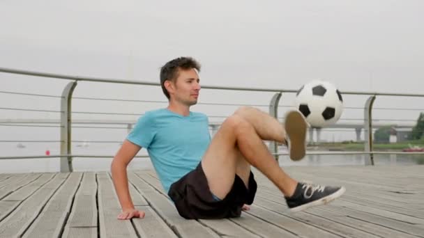 Young Man Soccer Player Sportswear Practicing Kicks Ball Sitting Waterfront — Stock Video