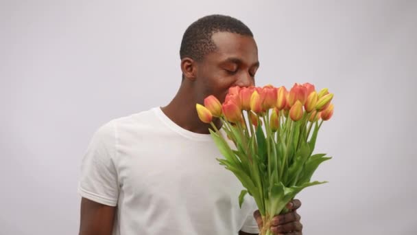 African American Smiling Man Sniffing Flowers Showing Pills Allergy White — Wideo stockowe