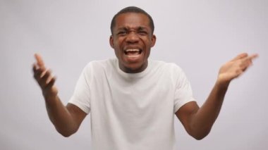 African american man says what and gesturing his hands on white background. A gesture of indignation, misunderstanding, question, demand for an answer. Confused expressive young man looking at camera.