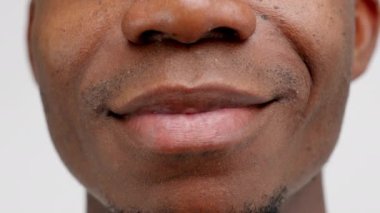 Macro shot of african american man smiling in front of camera, showing white teeth and positive facial expressions, mouth close-up view. Male feeling happy, having short haired trimmed beard.