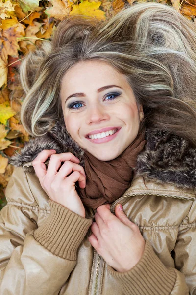 Young beauty lying on leaves in autumn — Stock Photo, Image
