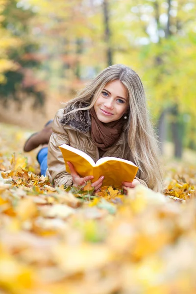 Young woman reading lying on leaves Stock Photo