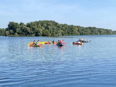 Nehirde kırmızı kanoyla kayak yapmak, kayıkla kürek çekmek, kano kullanmak, açık havada dolaşmak.