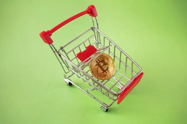 ビットコインで購入するためのショッピングトロリー 緑の背景にトロリーのベビーチェアの暗号通貨ビットコイン トップビュー — ストック写真