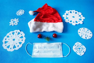 Noel Baba 'nın kırmızı şapkası, Noel Baba' nın kırmızı şapkası Noel baloları burun ve tıbbi yüz maskesi olarak yeni yıl ağacı dalı ve kağıt kar taneleri, yeni yılda zenginlik ve sağlık, yakın çekim.