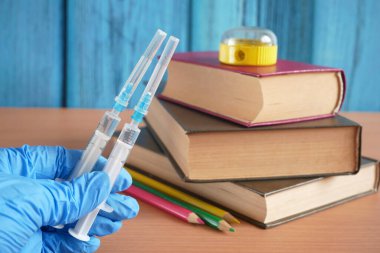 Aşı şişeleri ve şırıngaları kitap yığını ve okul malzemelerinin yanında ziraat uzmanı covid-19, çocuk aşısı konsepti, yakın çekim