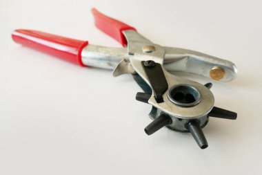 Beyaz arka planda izole edilmiş bir yumruk kullanarak kayıttaki delikler. Kemerli Delik Yumruklayıcı Güç Desteği Ağır Görevli Dönen Gözlü Yumruk Kerpeteni. Yakın çekim.