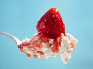 Çilek soslu süzme peynir mavi arka planda kaşık, sağlıklı kahvaltı, yakın plan.