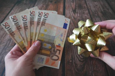 Eller nakit para yığınını alır ve ahşap zemin üzerinde eğilir, para hediye konsepti, yakın plan