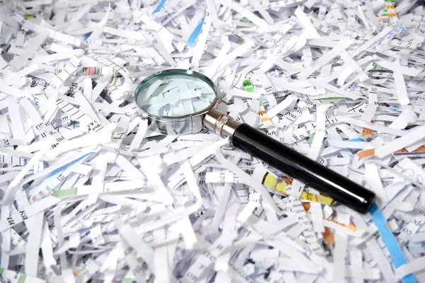 Shredded documents to protect confidential information and magnifying glass, background, concept, top view