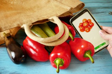 Organik sebzeler ve pamuk torba ve cep telefonundaki meyveler, çevrimiçi pazar, evde yeşil market teslimatı, sıfır atık kavramı, yakın çekim