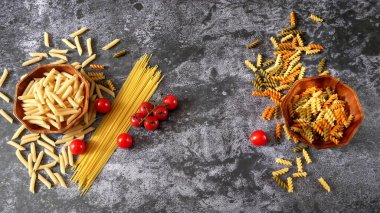 Çeşitli makarna türleri (fusilli, penne, cavatapi, cannelloni, spagetti) siyah arka plan, çiğ makarna seti ve domates, set, koleksiyon, yakın çekim, üst görünüm)