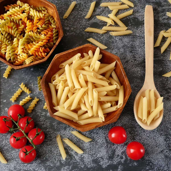 Çeşitli makarna türleri (fusilli, penne, cavatapi, cannelloni, spagetti) siyah arka plan, çiğ makarna seti ve domates, set, koleksiyon, kapanış