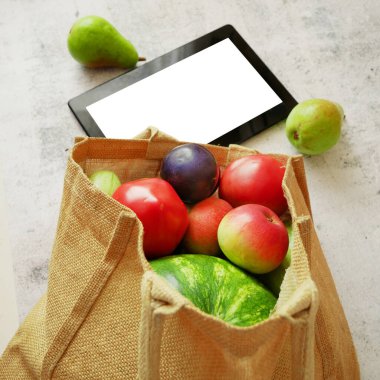 Organik sebzeler ve meyveler pamuk torbası ve tablet bilgisayar, çevrimiçi pazar, ev konseptinde yeşil market teslimatı