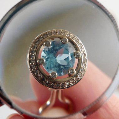 Büyüteç altında eski bir küpe ve siyah arka planda mücevher yığını, rehinci konsepti, kuyumcu dükkânı konsepti, yakın plan.