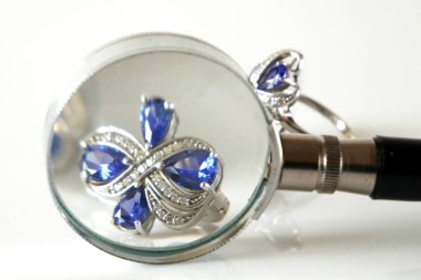 Büyüteç altında klasik küpe ve siyah arka planda mücevher yığını, rehinci konsepti, kuyumcu dükkânı konsepti, yakın plan.