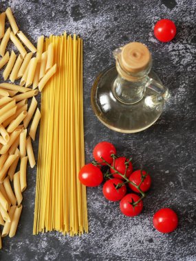 Çeşitli makarna çeşitleri, ahşap zemin üzerinde çiğ makarna seti ve domates, set, yakın çekim