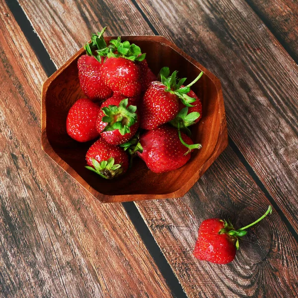 group strawberries with strawberry leaf on wooden background, closeup