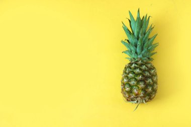 Sarı zemin üzerinde, fotokopi alanı ve üst görünümü olan olgun ananas.