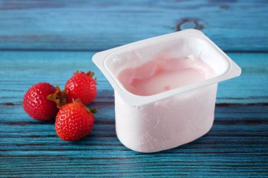 Tahta arka planda taze yoğurt, çilek ve yabanmersini. Sağlıklı Kahvaltı Konsepti. Yakın çekim