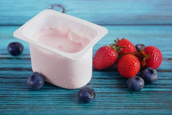 Tahta arka planda taze yoğurt, çilek ve yabanmersini. Sağlıklı Kahvaltı Konsepti. Yakın çekim