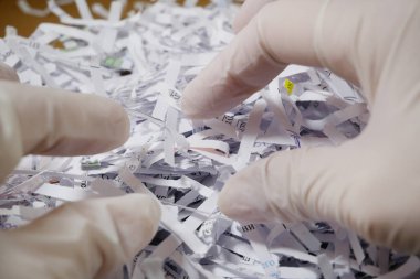 Beyaz eldiven ve parçalanmış kağıt yığınını teslim et. Yakın plan. 