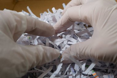 Beyaz eldiven ve parçalanmış kağıt yığınını teslim et. Yakın plan. 