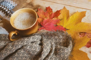 Sonbahar yaprakları, sabah kahvesi ve ahşap arka planda sıcak bir eşarp, sonbahar havası konsepti.