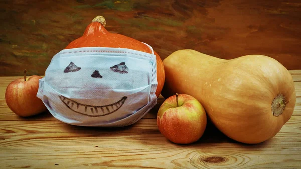 group of pumpkins, face medical masks for protection from coronavirus and apples. Halloween 2022 concept. Halloween party concept