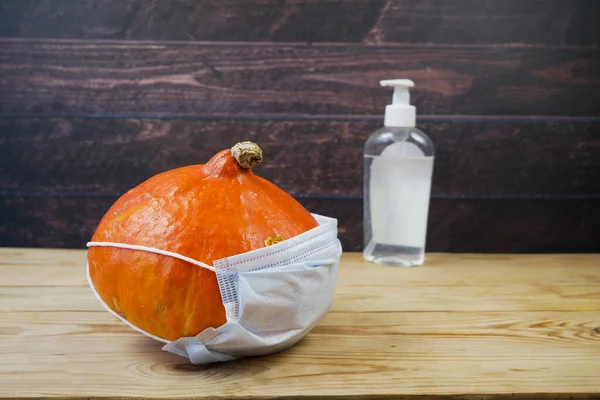 pumpkins, face medical masks for protection from coronavirus, sanitizer. Halloween 2022 concept. Halloween party concep