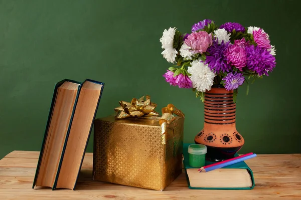 World Teacher\'s day concept. Flowers bunch, pencils globe and books pile, still life