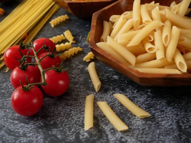 Çeşitli makarna çeşitleri, çiğ makarna seti ve domates seti. Yakın çekim.