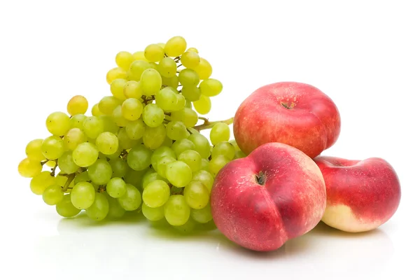 Pesche piatte cinesi e uva verde su sfondo bianco — Foto Stock