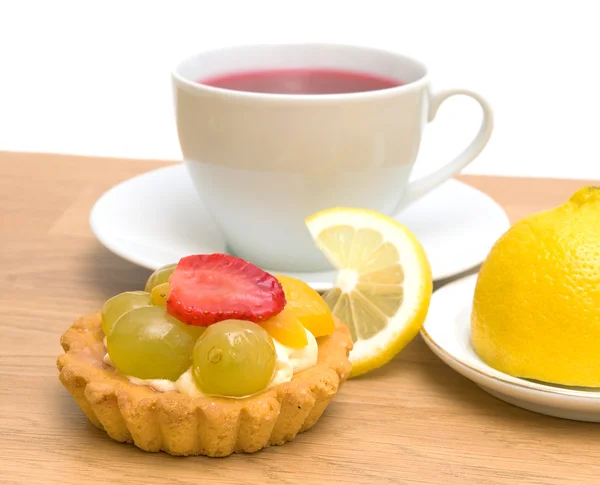 Pastel, limón y una taza de té de frutas sobre un fondo blanco — Foto de Stock