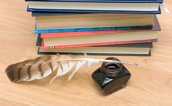 Caneta, tinta e livros sobre uma tábua de madeira — Fotografia de Stock