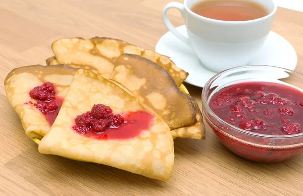 Pannenkoeken met frambozenjam en een kopje thee — Stockfoto