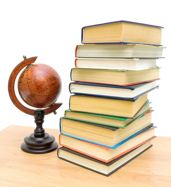 Антикварный глобус и стопка разных книг — стоковое фото