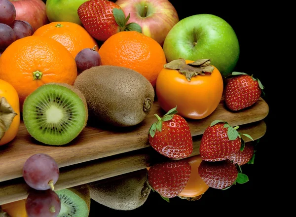 Fruit en bessen op een zwarte achtergrond met reflectie close-up — Stockfoto