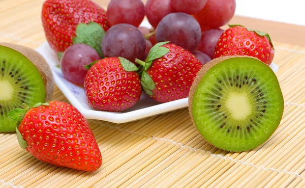 Saftigt mogna bär och frukt - kiwi, jordgubbar och vindruvor. — Stockfoto