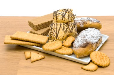 Beyaz bir tabak içinde farklı pasta ve şekerlemeler ürünler